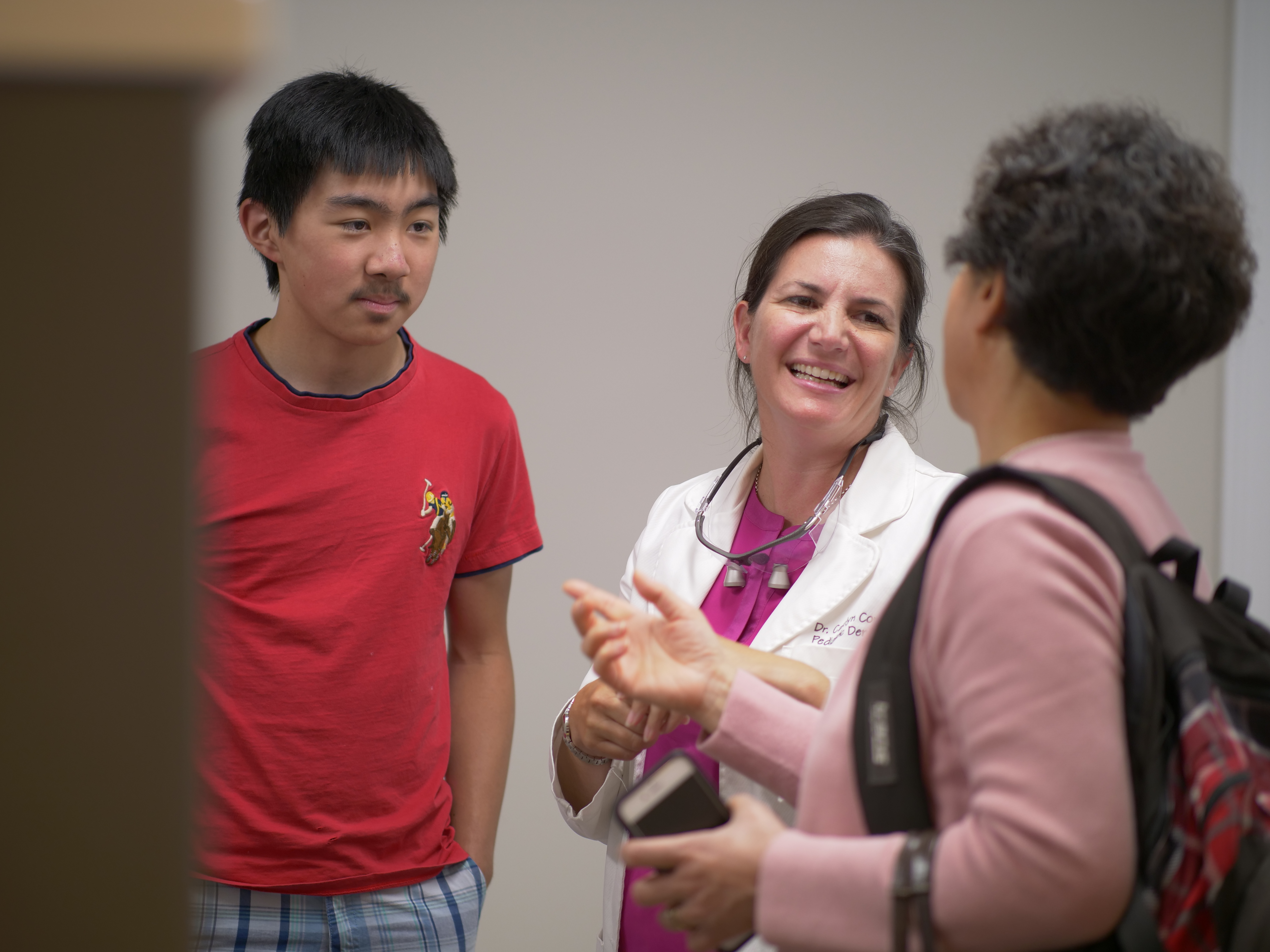 Doctor interacting with a patient and parent in a dental office, discussing orthodontic care and flexible spending accounts at Coppe + Sears Pediatric Dentistry and Orthodontics in Lexington, MA.
