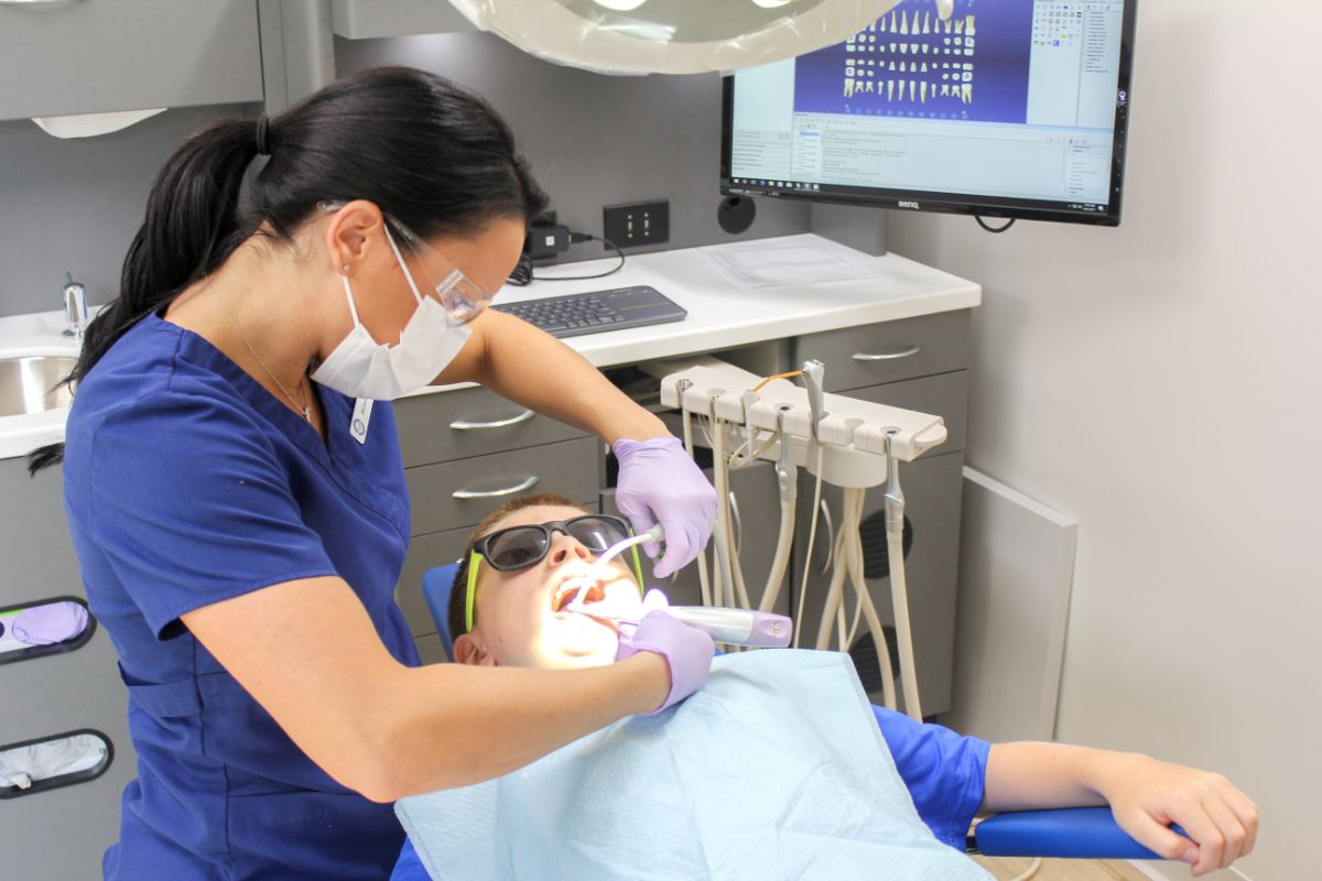Dental assistant examining child patient in orthodontic office, emphasizing pediatric dentistry and oral health care at Coppe & Sears Orthodontics.