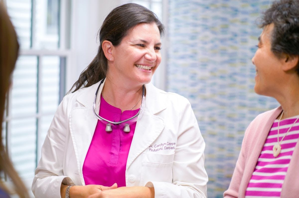 Dr. Carolyn Coppe, pediatric dentist in Lexington, smiling and engaging with a patient in a dental office setting, emphasizing patient care and orthodontic advice.