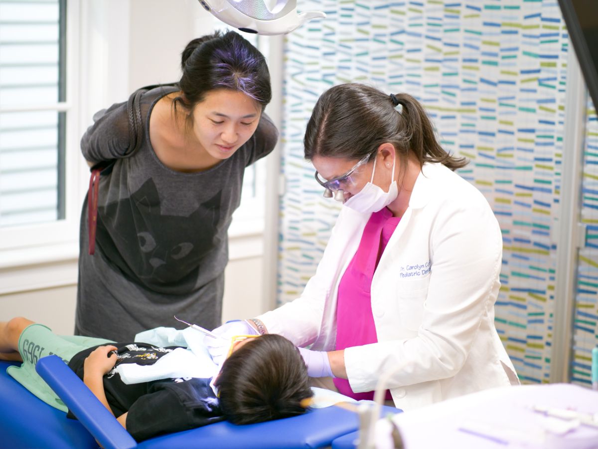 Child undergoing dental examination with pediatric dentist Dr. Carolyn Coppe in a modern office, mother observing, emphasizing pediatric dentistry and orthodontics in Lexington.