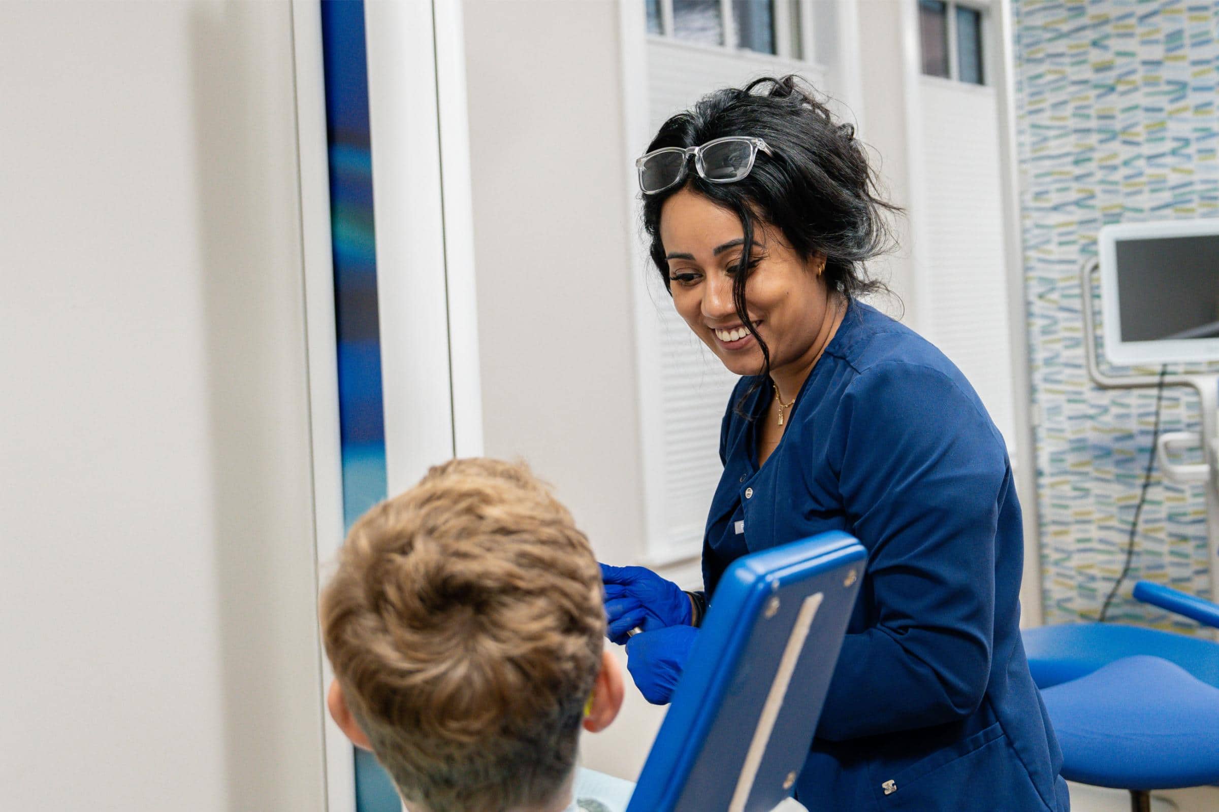 Dental hygienist interacting with a young patient in a pediatric dental office, emphasizing the caring approach of Coppe and Sears Pediatric Dentistry in Lexington, MA.