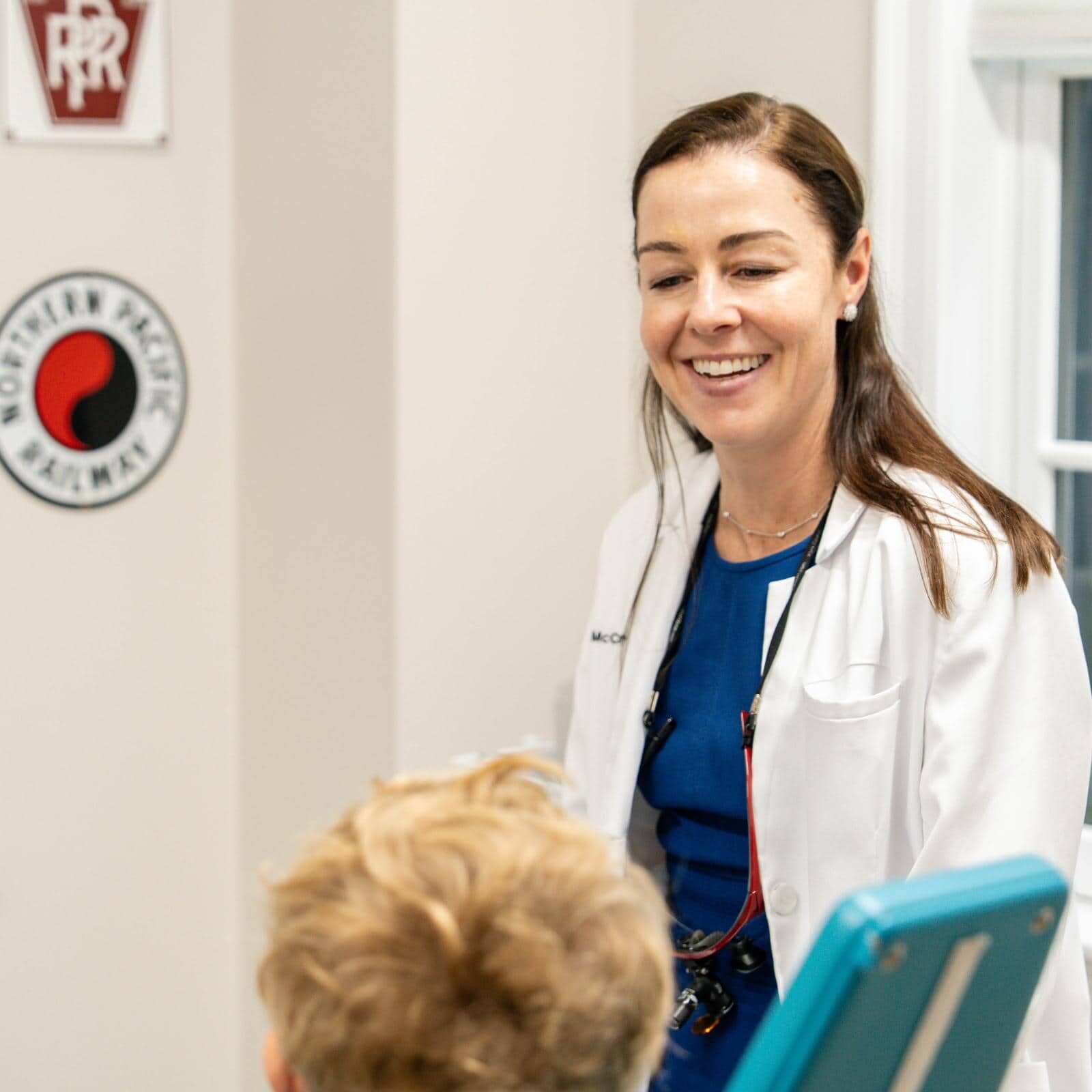 Dr. Coppe smiling and interacting with a young patient in a pediatric dentistry office, promoting a friendly and supportive environment at Coppe + Sears Pediatric Dentistry and Orthodontics in Lexington, MA.
